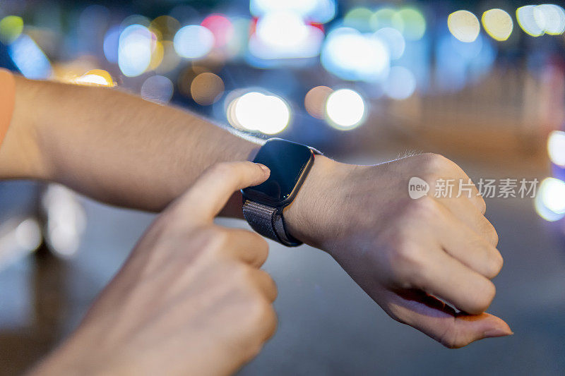 An Asian young man hand using a smart watch at night in the outdoors